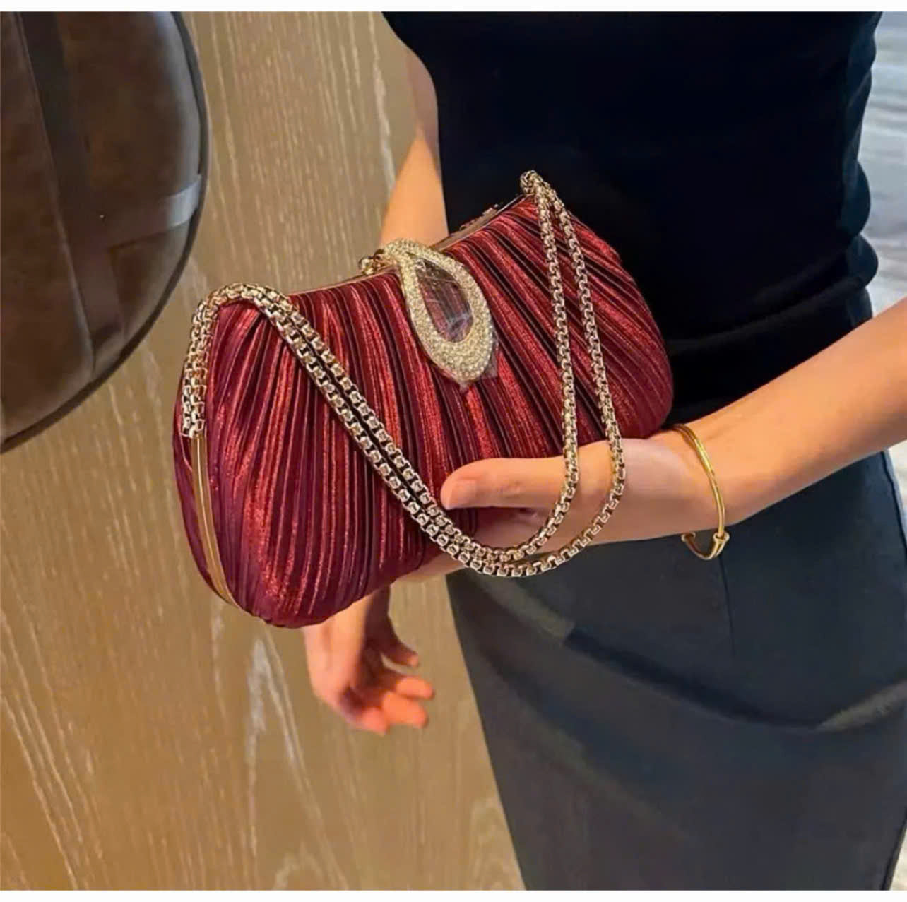 Premium women's party handbag featuring a pleated design and sparkling stone embellishments.